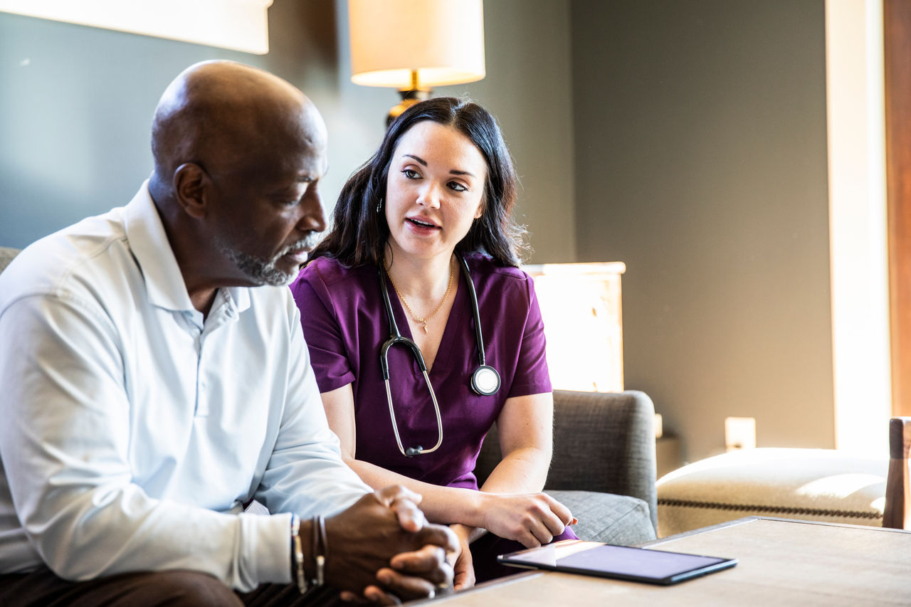 A healthcare provider and a patient sitting and talking with a tablet in front of them