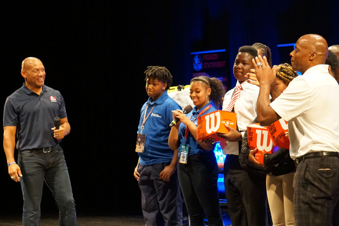 Aenneas Williams speaking on stage with kids