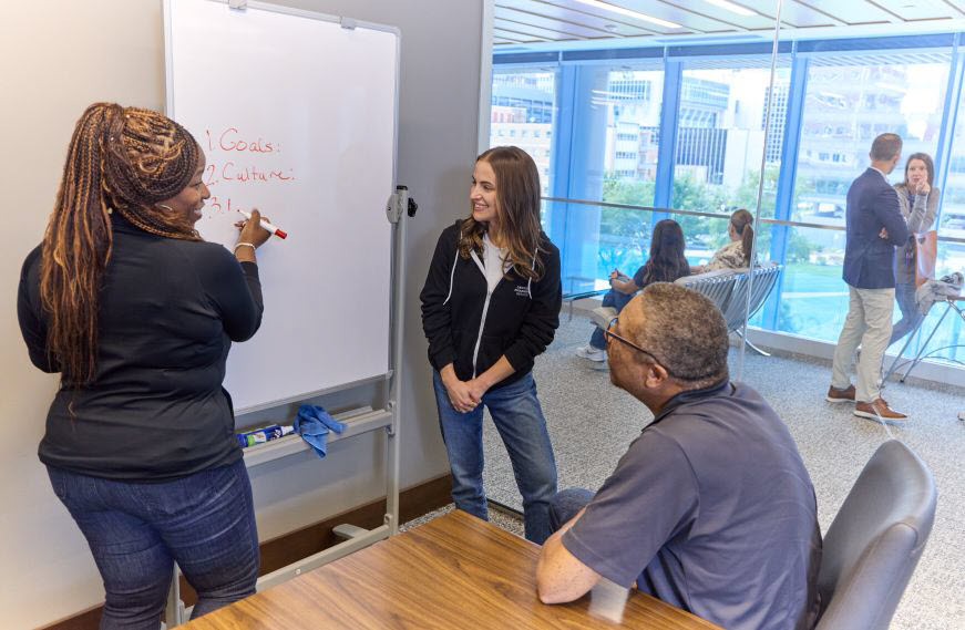 Employees in office talking in front of a whiteboard