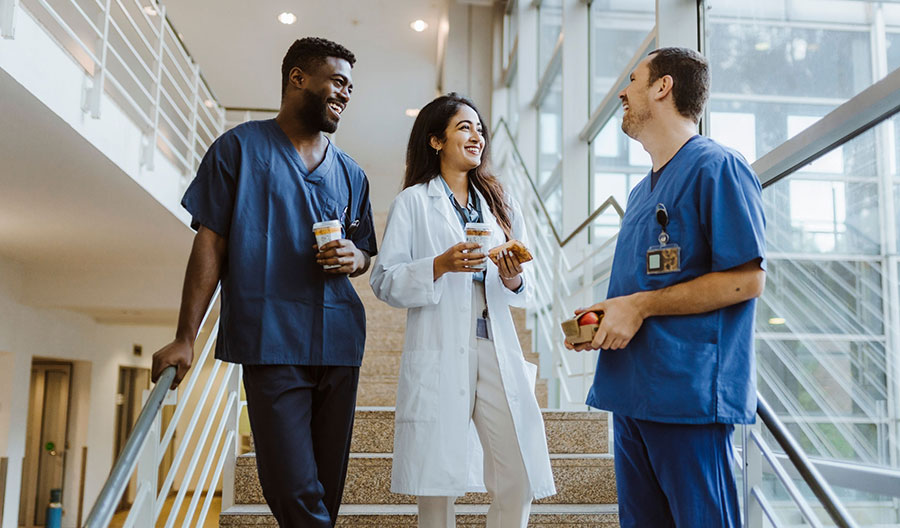 Healthcare colleagues chatting on a stairwell during a break, holding drinks and food