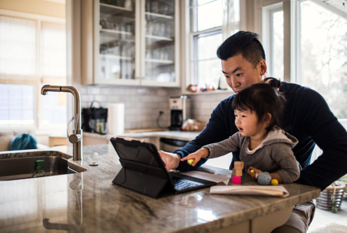 father and daughter sit at counter with laptop