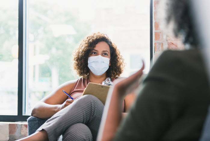 masked woman listens to individual