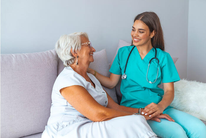 woman and caregiver sit on sofa