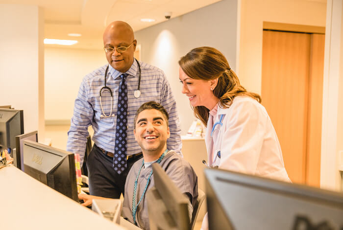 providers gather around computer inside hospital.
