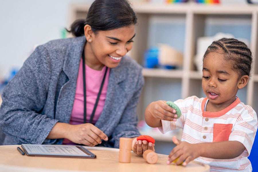 Care manager interacting with a child during play with educational toys