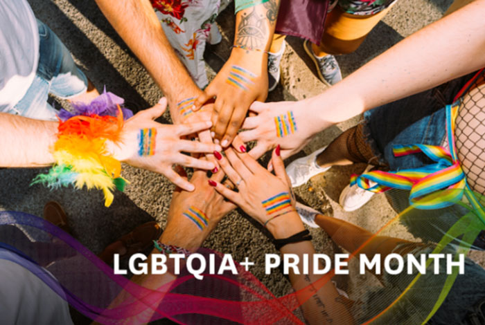Hands overlapping symbolizing support for LGBTQIA+ Pride Month