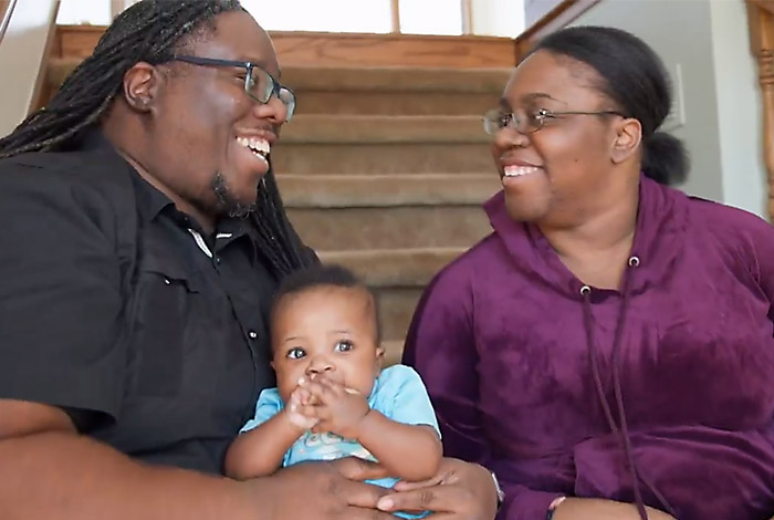 Father and mother looking at each other laughing, father holding their baby