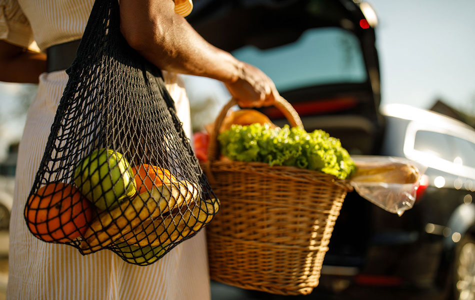 Woman carrying two bags of fresh fruits and vegetables