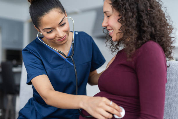 nurse listening to pregnant patient's heartbeat