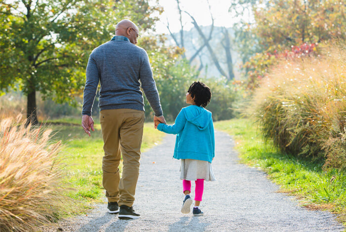 Grandfather and granddaughter walk in the park