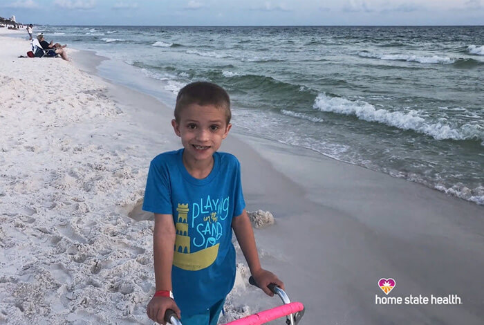 little boy with walker on beach