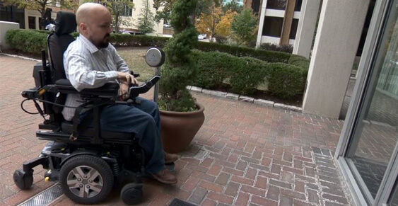 man on wheelchair enters building.