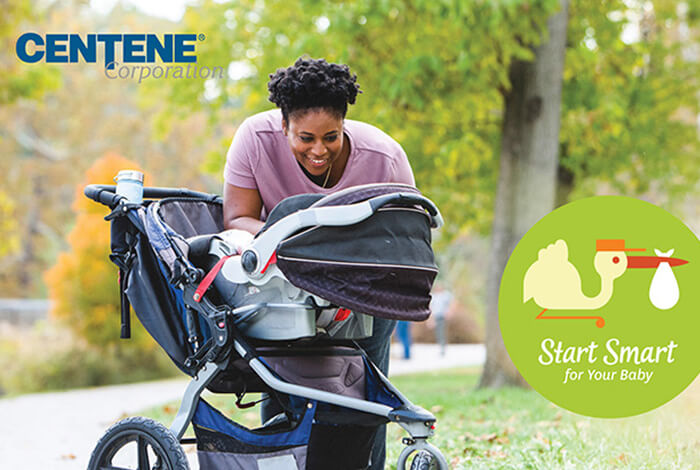 African American mother leaning over a baby stroller in park