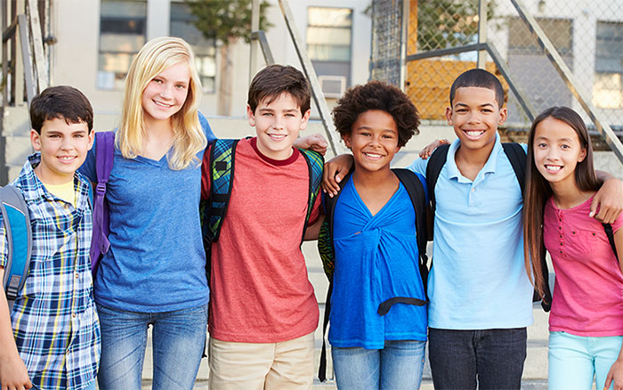 A group of smiling elementary students standing with backpacks