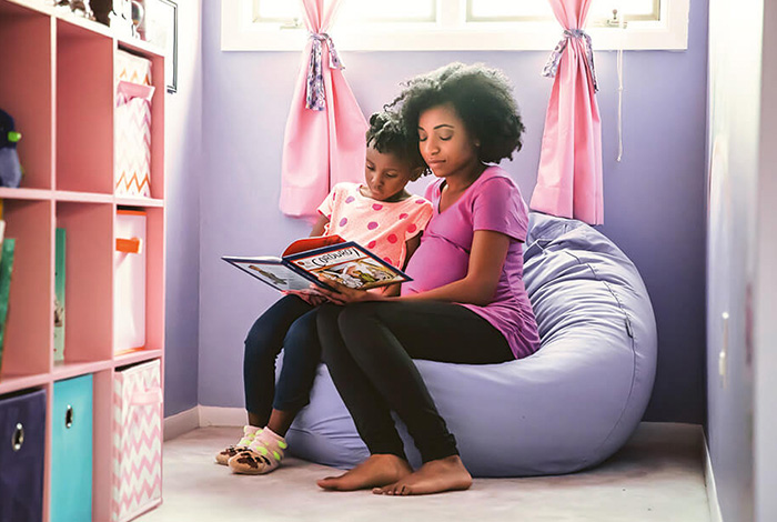 Pregnant mother reading to young child