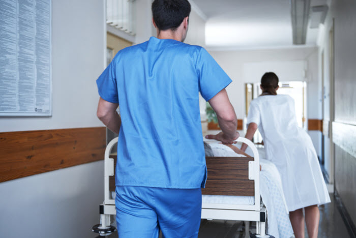 healthcare workers wheel gurney down hospital hallway