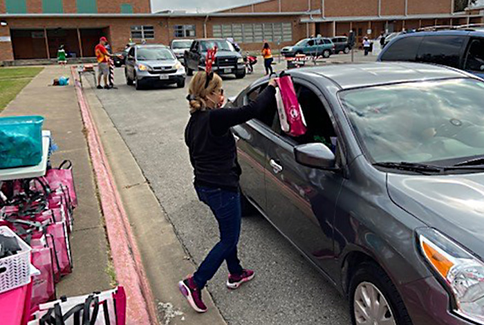 A volunteer handing out gift packages at drive-through outreach event. 