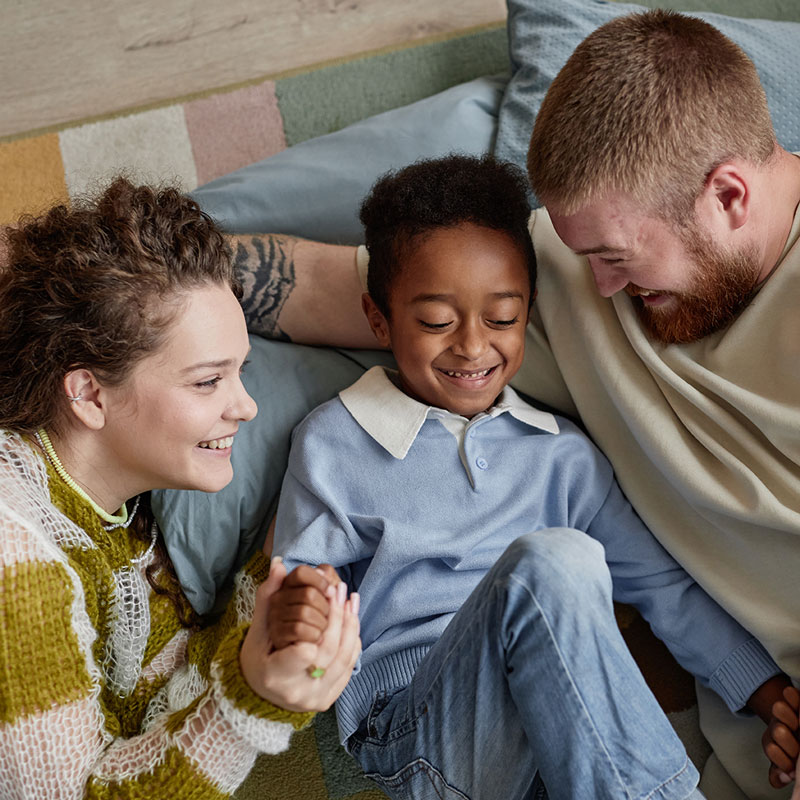 mother, son, and father holding hands and laughing