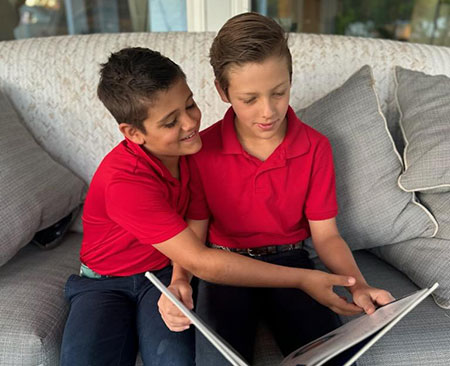 two boys reading a book  on a couch