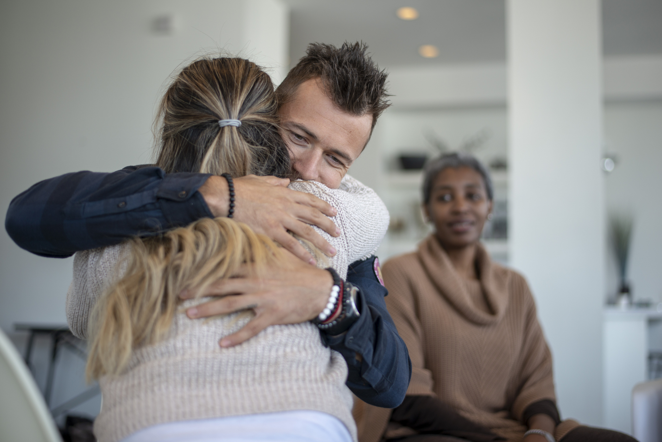 two participants in a support group hugging, smiling