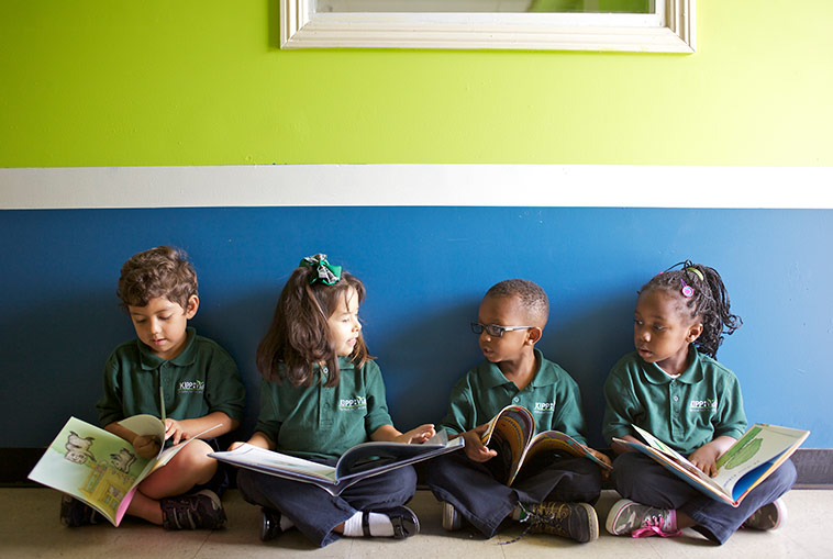 kids in school uniforms sitting on the floor reading