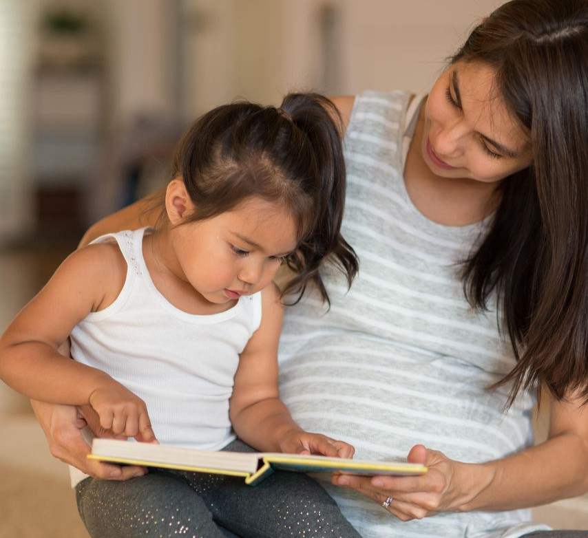 pregnant woman reading to a toddler