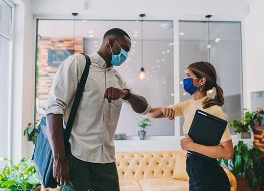 masked office workers bumping elbows