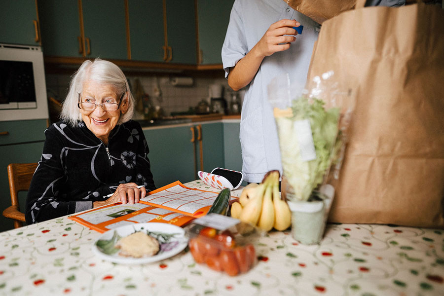 A senior woman at a table with groceries in front of them